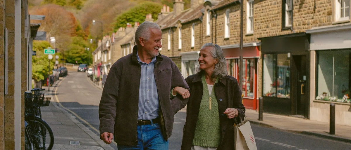 Older couple walking arm in arm along a village high street on an autumn morning